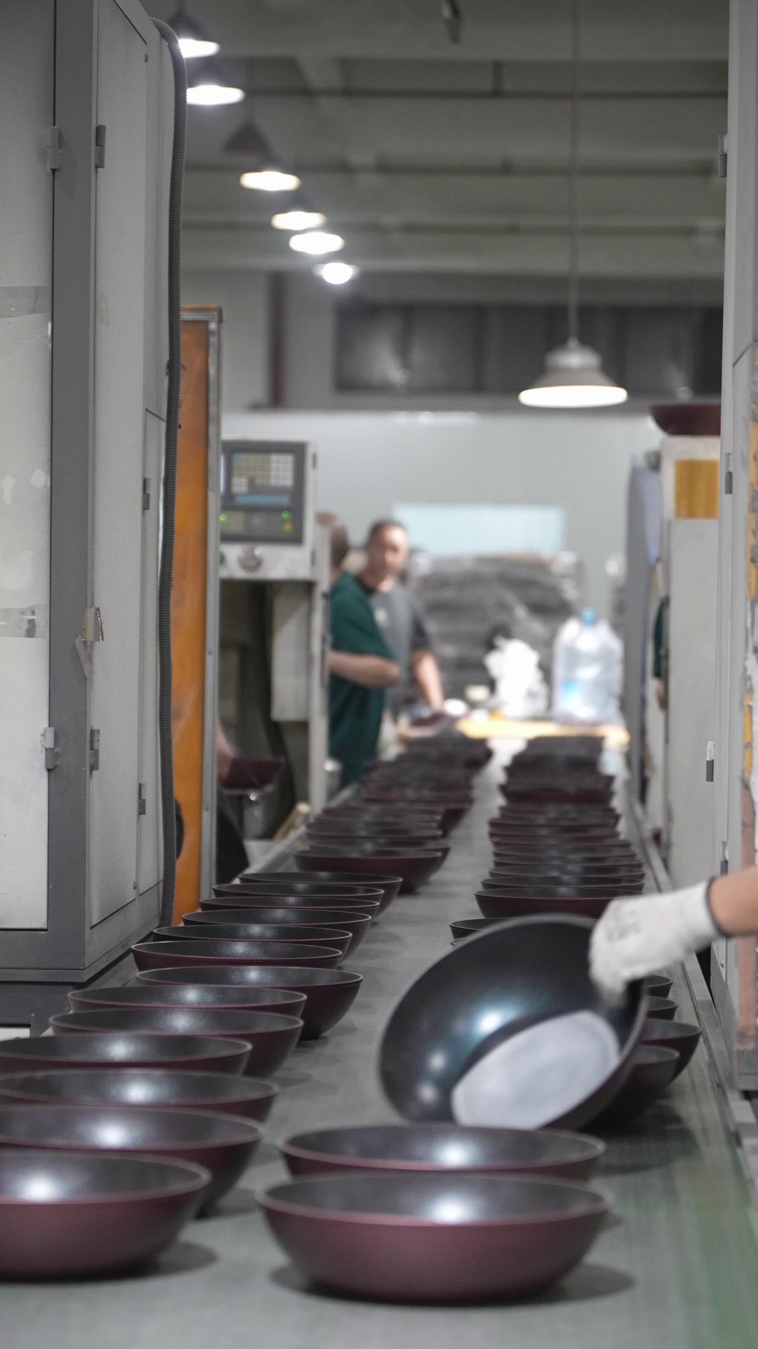 Rows of cookware moving through the YOUME factory production line